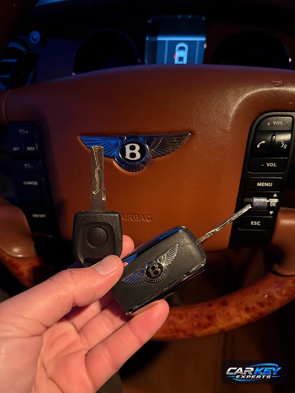A new laser-cut transponder key next to the worn original Bentley flip key, at the steering wheel in Nampa