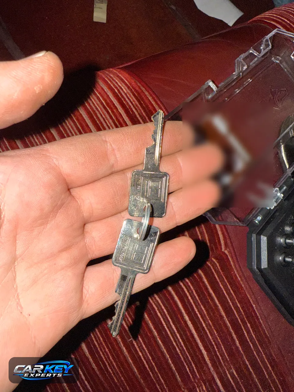 Two newly cut metal keys for an older car, held in a hand in Kuna