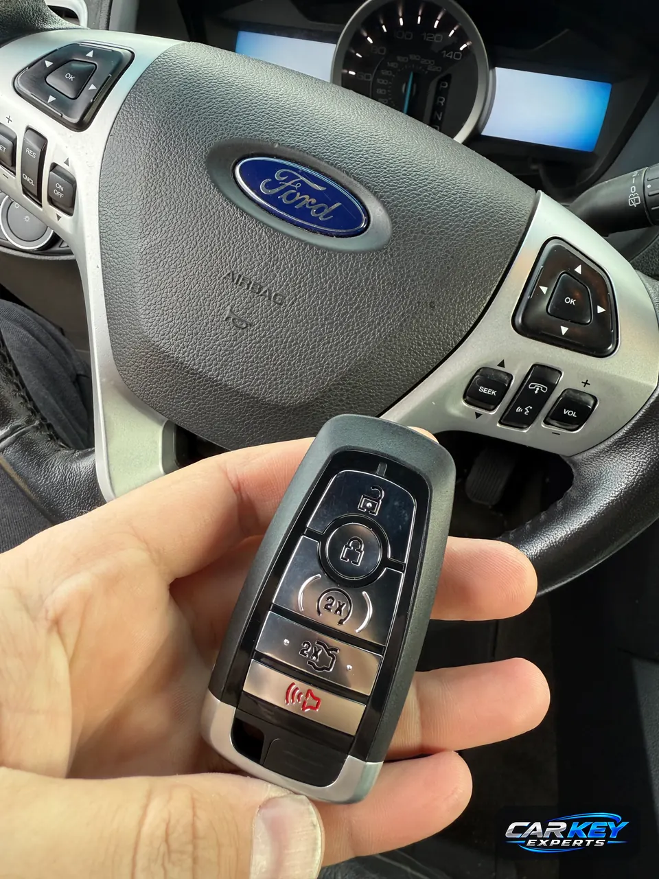 A Ford smart key with five buttons, remote start among them, at the steering wheel of a Ford Explorer in Meridian
