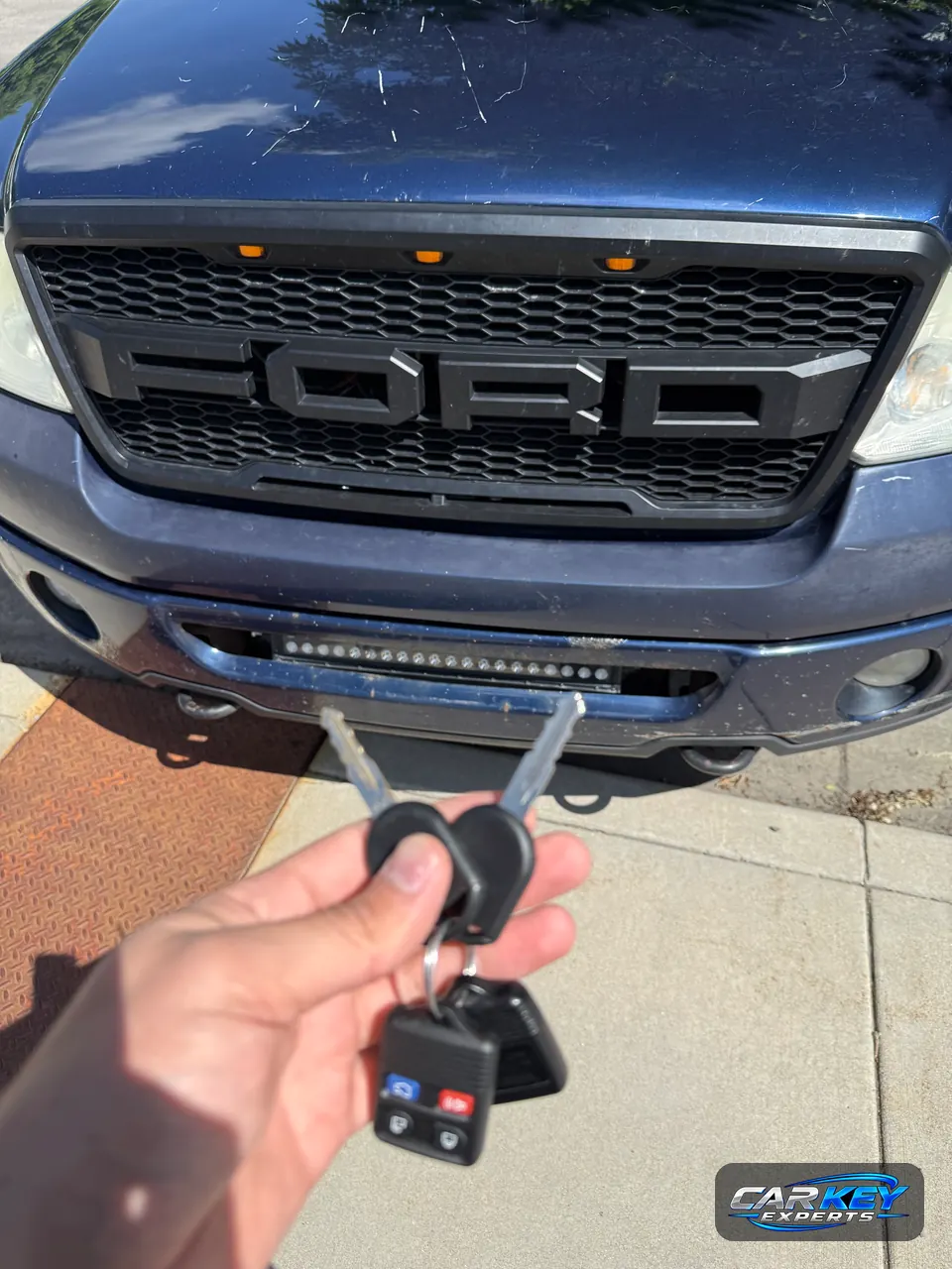 Two new transponder keys and a Ford keyless remote held in front of a Ford F-150 in Eagle