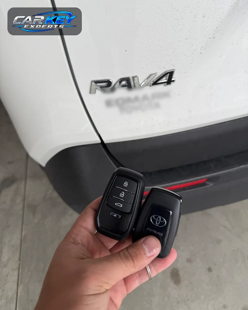 A new spare smart key beside the original at the back of a white Toyota RAV4